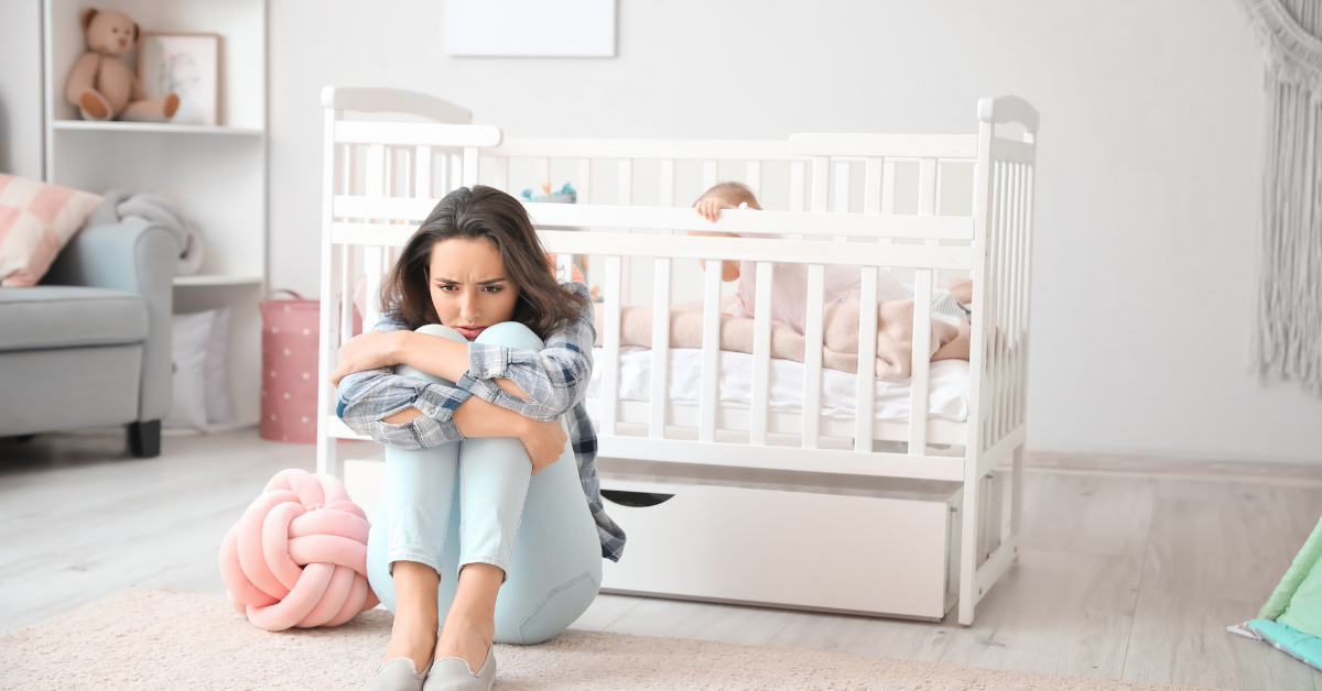 mother sitting in front of baby crib