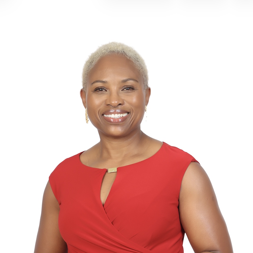 Smiling woman with short blonde hair wearing a sleeveless red dress stands against a plain white background.
