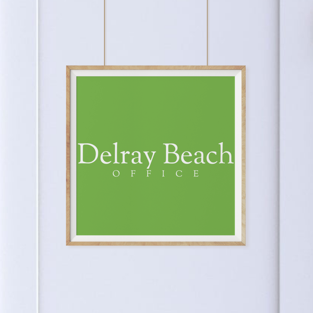 A square sign with a green background and white text that reads "Delray Beach Office," framed and hanging on a light-colored wall.