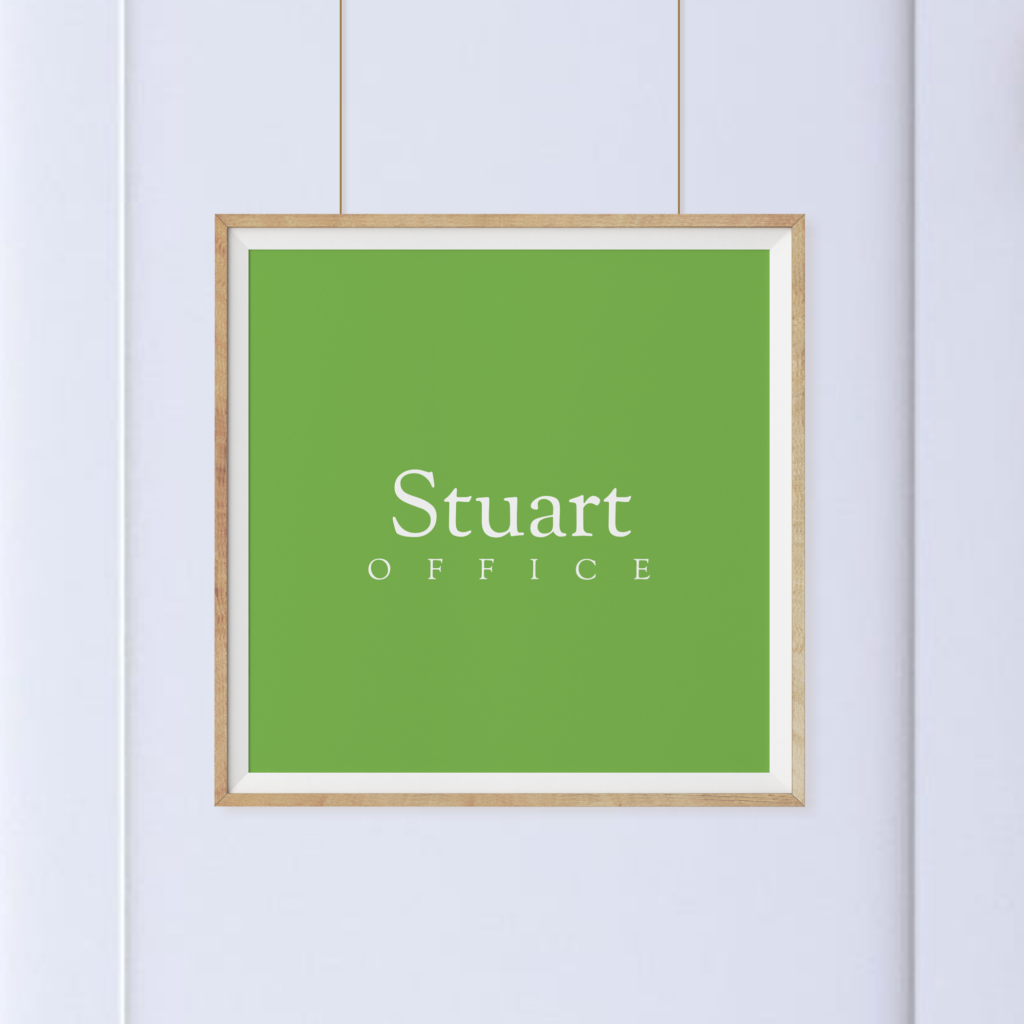 A framed green sign with the words "Stuart OFFICE" in white text, hanging on a light-colored wall.